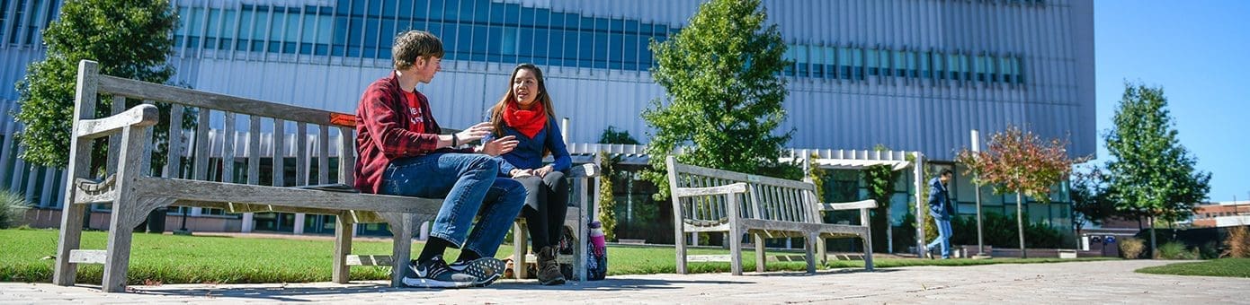 NC State University students sitting on a bench on campus