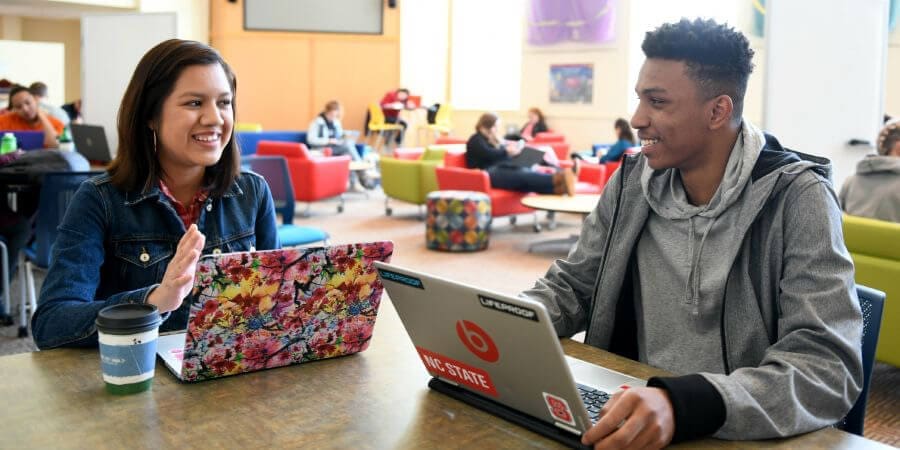 Two smiling NC State students with laptops