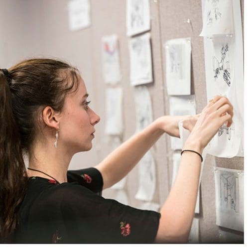 An ECU interior design student hangs drawings by her team for a hypothetical showroom in Chicago’s Merchandise Mart. (Photos by Cliff Hollis)
