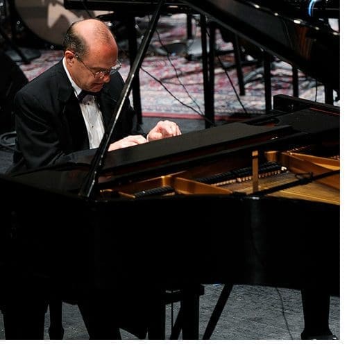 WCU’s late Chancellor David O. Belcher performs on piano in the performance hall of the university’s arts center.