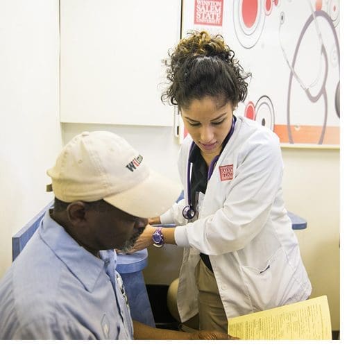 A WSSU School of Health Sciences student assists a patient at the Rams Know H.O.W. mobile unit.