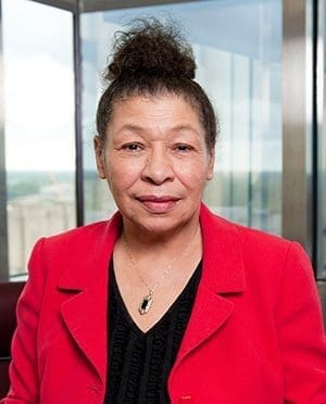 Sylvia Flack, smiling with a wall of windows behind her