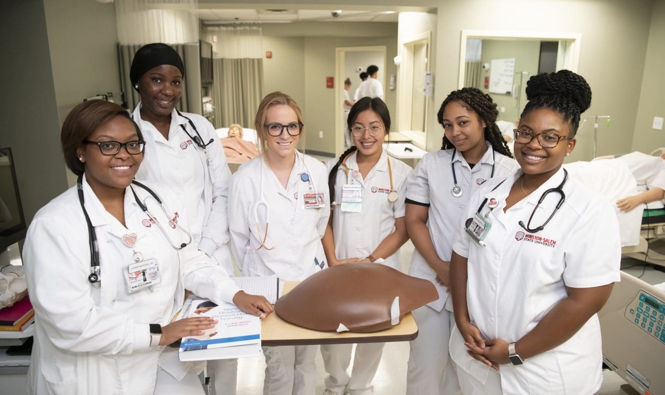 A group of nursing students gather around a model torso.