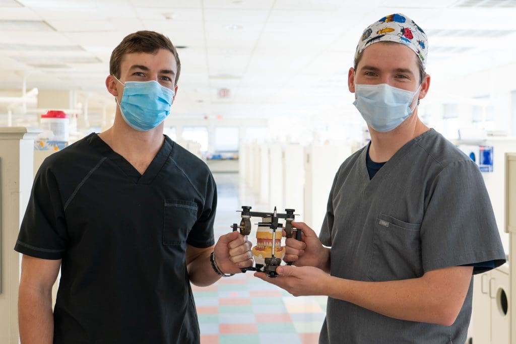 Two Fellows stand side by side holding dental mould