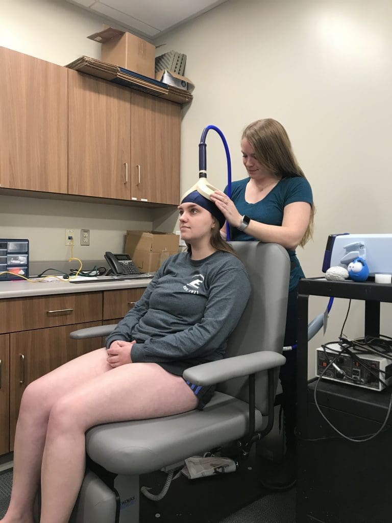 Rhea attaches electrical equipment to a patient's head