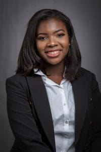 Portrait of Joshualan Mikayla Parrish against a gray background.