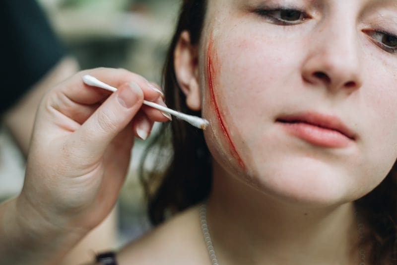 Makeup applied to make a woman's cheek look as if it's been gashed