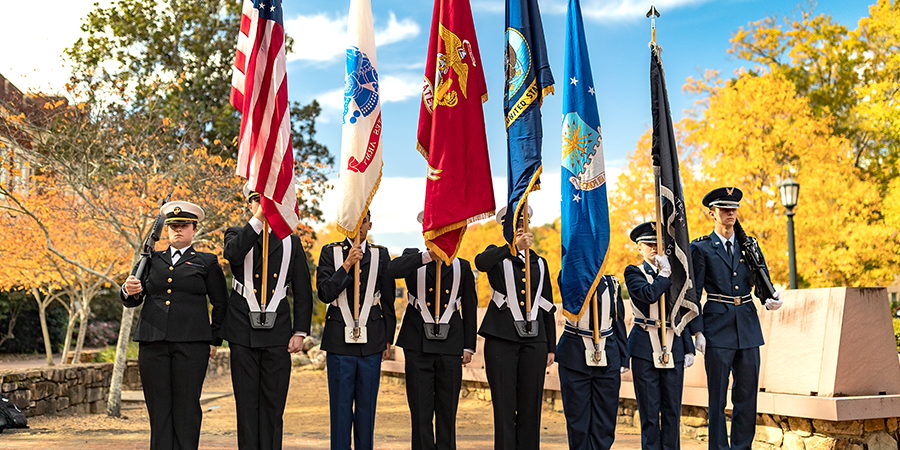 ROTC students in military uniforms holding U.S. and military flags