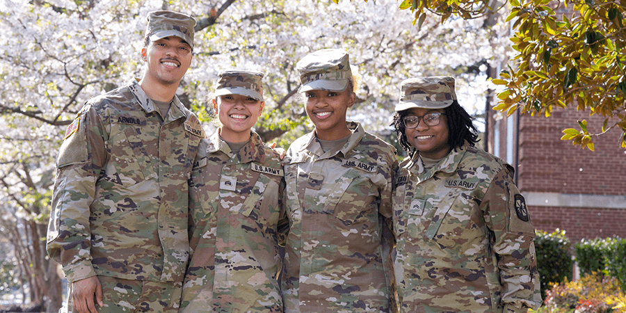 Four smiling students wearing military uniforms