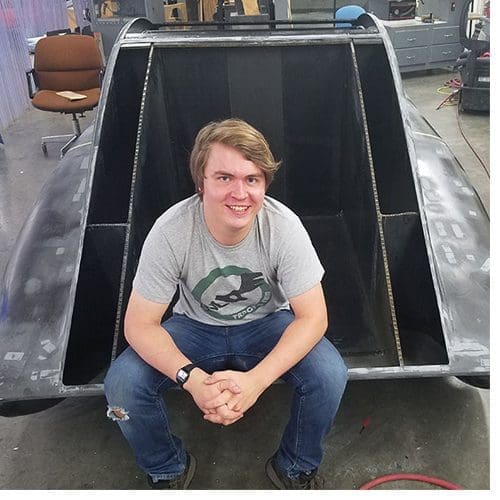 Industrial design major and Raleigh native John Lalevee poses with the unfinished solar vehicle, ROSE, which he helped design during the 2017–18 year. Photo submitted